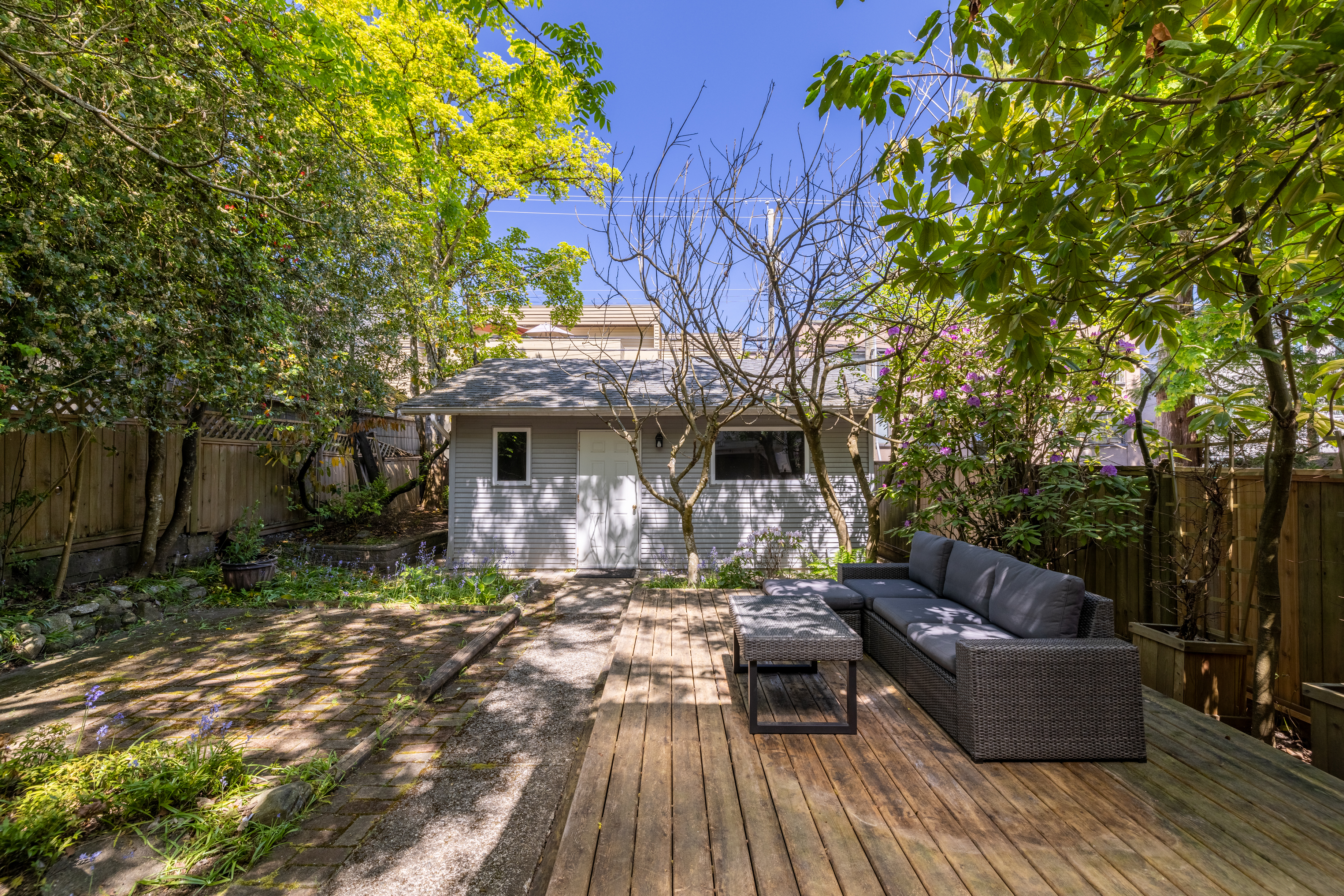 Back garden with wood deck, brick patio and mature plantings