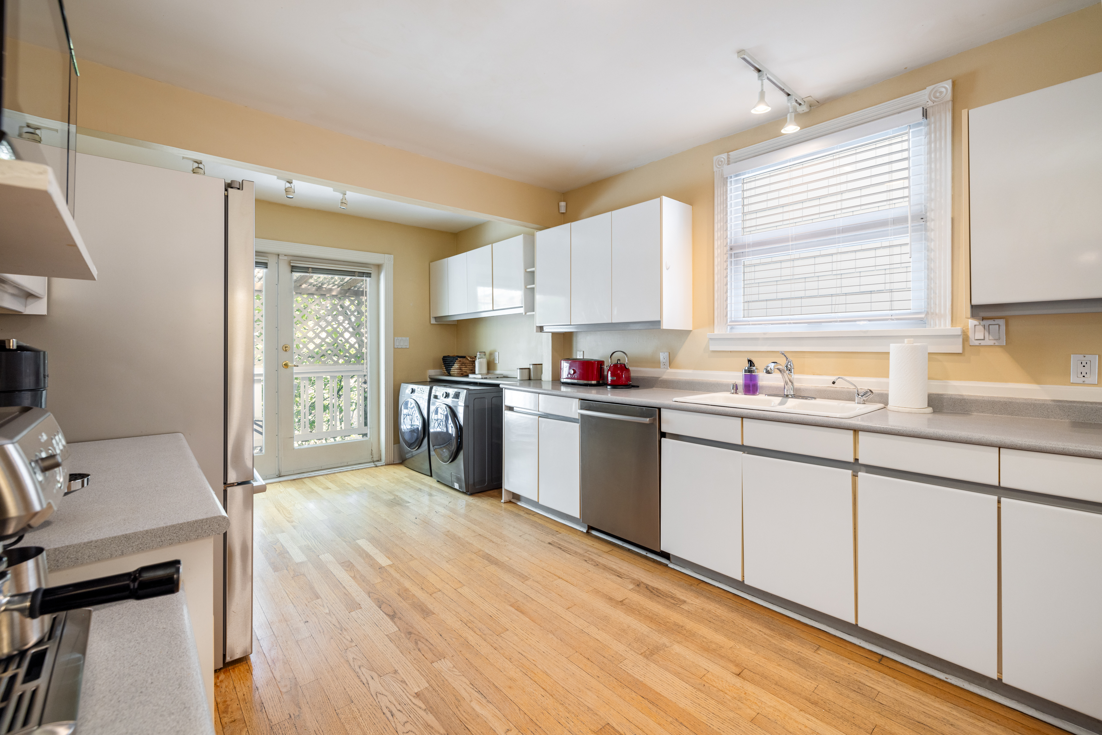 Kitchen with white cabinets, stainless steel appliances and access to the back deck